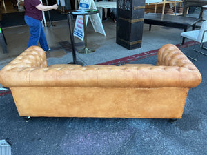 This is a leather Chesterfield tufted sofa with rolled arms in a caramel color measuring 84 inches long