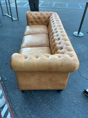 This is a leather Chesterfield tufted sofa with rolled arms in a caramel color measuring 84 inches long