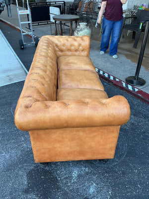This is a leather Chesterfield tufted sofa with rolled arms in a caramel color measuring 84 inches long